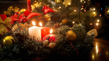 Toned image of burning candles and Christmas wreath on winter holidays