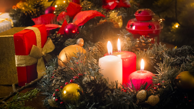 Toned image of three burning candles, gifts and wreath on Christmas eve