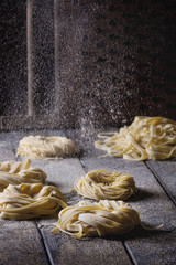 Variety of italian homemade raw uncooked pasta spaghetti and tagliatelle with sprinkling semolina...