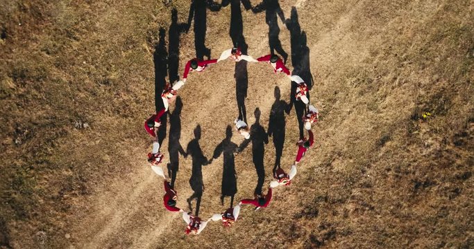 Aerial view: Top down view. A team of dancers circling in dance in the glade