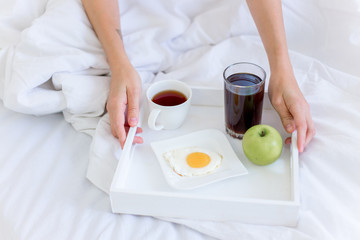 Young beautiful woman having breakfast in bed