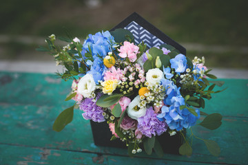 Image of beautiful flowers arrangement with blue hydrangea, white eustoma, spray roses, carnations on the wooden table