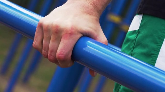 Close-up - Male Athletic Man Exercising on Parallel Bars. Street Workout and Outdoors Training.