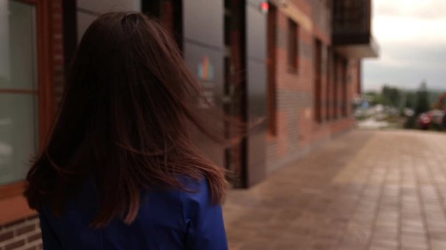 Portrait of stylish young brunette woman walking the streets of the city attractive Caucasian woman wearing a blue coat in the city.