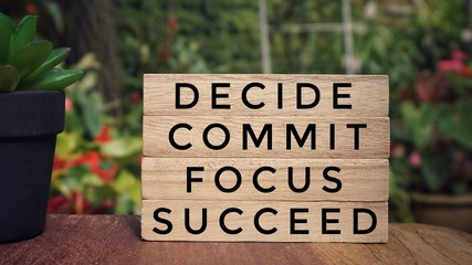 Motivational and inspirational quote - ‘DECIDE, COMMIT, FOCUS, SUCCEED’ written on wooden...