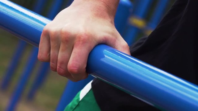 Street Workout. Close-up - Sporty Man Exercising on Parallel Bars in Outdoor Gym. Sports and Fitness.