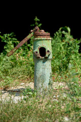 close up view of old grungy water fountain and green plants behind