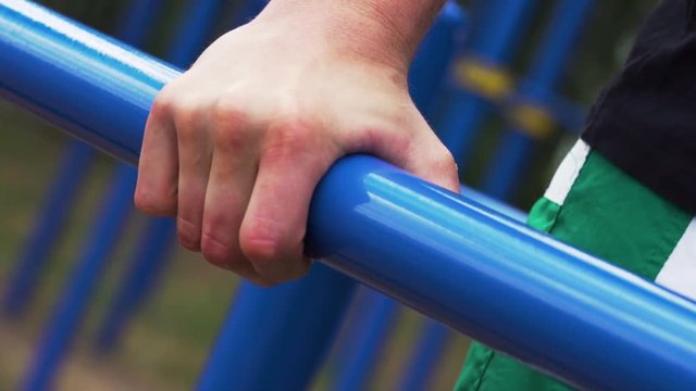 Close-up - Male Athletic Man Exercising on Parallel Bars. Street Workout and Outdoors Training.