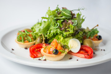 Fresh salad with salmon, olives, green, tomatoes and quail eggs