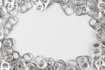 aluminium ring pull opener or ring tabs on white background, free space for text in middle. concept : recycle ringpulls for disable prostheses.