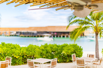 Typical bamboo hut and palm leaves standing at the white sand beach against background with beautiful sea and cloudless blue sky on a sunny day.
