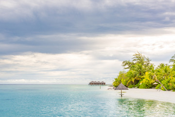 Beach umbrella on the beach atoll island Maldives. Calm tropical sunset