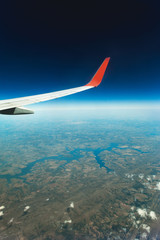 Side/top view of a airplane wing and the earth with a deep blue sky, a cold horizon and a green ground. Travel, Airplane, Vocation, transport, fly is the concept