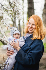 Portrait of a beautiful young woman with red hair, who is holding a newborn baby boy