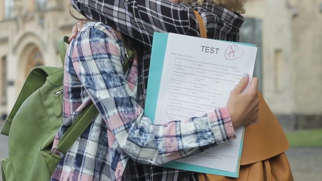 Girl having unexpected perfect mark in difficult exam, sharing good mood friend