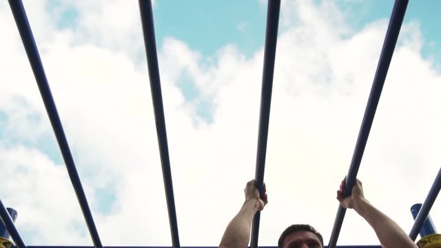 Slow Motion - Young Fit Man Engaged in Street Workout. Male Athlete Doing Pull Ups on Parallel Bars. Summer Training in Park