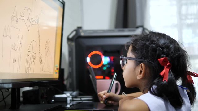 Asian little girl in Thai student uniform using pen tablet to drawing and digital painting with computer