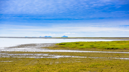 Beautiful isolated green colored Iceland lake with blue skies and puffy clouds. Reflection on water.
