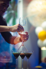 Hand holding glasses of bartender stack overlap of glasses of cocktails to prepare the exciting shot of burning fire flame, nightclub party serving cocktails wonderful night holiday