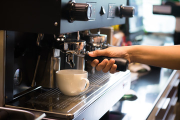Close up barista hands making coffee by coffee machine in coffee cafe. It's coffeemakers or coffee machines are cooking appliances used to coffee. Making Coffee Preparation Service Concept