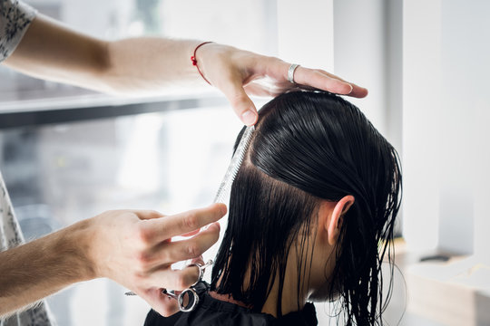 Male Hairdresser Smiling And Talking With A Customer While Making A New Haircut To Beutiful Young Brunette Woman