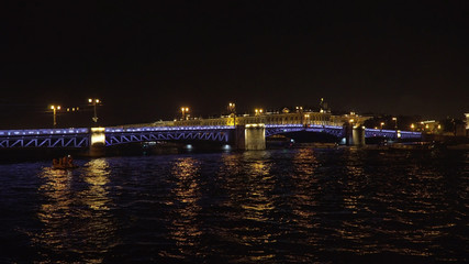 Fototapeta na wymiar Bridge over the river, illuminating the water with light from lampposts. City night scene with illuminated drawbridge over river. Saint Petersburg,Russia.