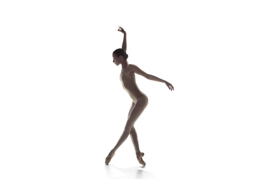 Fototapeta Young graceful female ballet dancer or classic ballerina dancing isolated on white studio. Caucasian model on pointe shoes