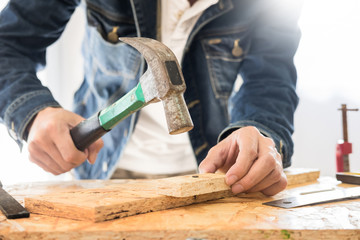 Carpenter working carefully looking at the plans work in carpentry. He is successful entrepreneur at his workplace. hammering a nail Supports On Building Site work with cutter.