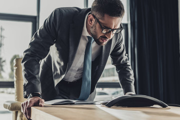 angry adult businessman shouting at speakerphone at modern office