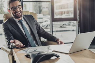 handsome happy businessman using speakerphone at modern office