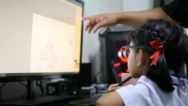Asian little girl in Thai student uniform using pen tablet to drawing and digital painting with computer