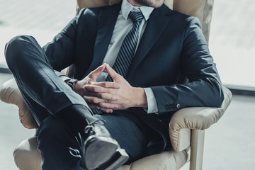 cropped shot of businessman relaxing on luxury armchair at modern office
