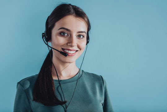 attractive smiling female call center worker looking at camera isolated on blue