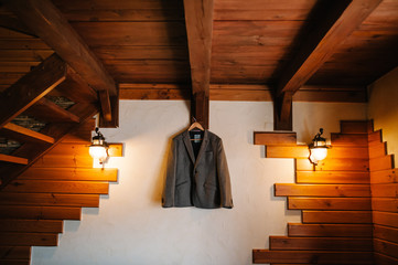 A man's jacket  on a hanger or on a rack on the background white and brown wooden wall in the room.