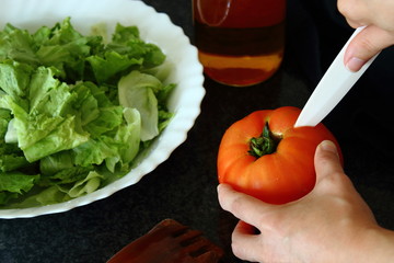 Close up on female hands cutting tomato, making salad.