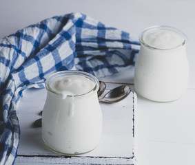 glass jars with homemade yogurt on a white wooden board