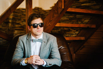 Imposing well dressed in suit, sunglasses man in a luxurious apartments with classic wooden...