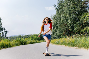 Beautiful skater woman riding on her longboard in the city