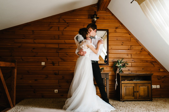 Loving couple, bride and groom hugging and kissing indoors. Wedding Morning.