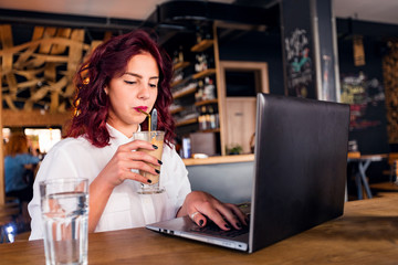 Young student girl working with laptop at coffee shop