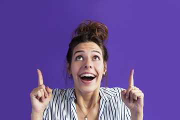 Happy news! Cheerful reaction, happy face of a young emotional woman on a purple background in a...