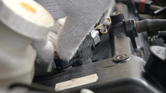 Close up shot mechanic hands are spinning bolt of car spark plug socket
