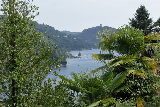 A landscape of Lake Orta, in northern Italy, with trees and mountains on the foregroud as a frame