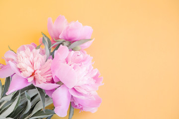 Bouquet of pink peonies on a cream background, top view, copy space