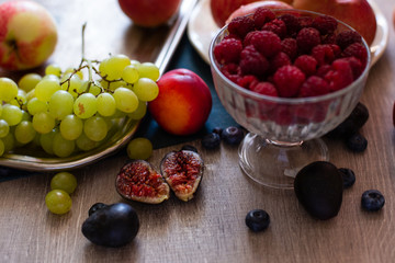 Assortment of Ripe Juicy Fruits on Wooden Table. Organic Raspberries,  Apples, Figs, Grapes - Summer dessert or Snack. Healthy Eating Concept