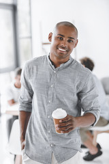 portrait of smiling african american businessman with coffee to go in office