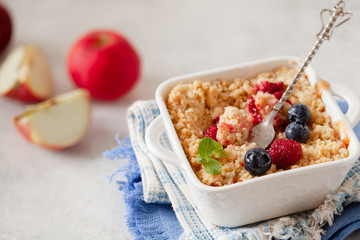 Traditional British apple crumble on portion baking dish with fresh berries