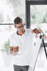 young focused businessman making presentation at white board in office