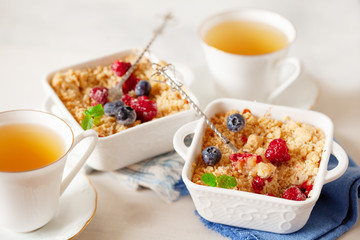 Traditional British apple crumble on portion baking dish with fresh berries