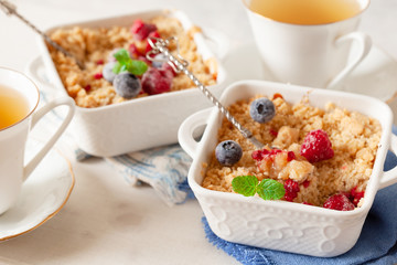 Traditional British apple crumble on portion baking dish with fresh berries
